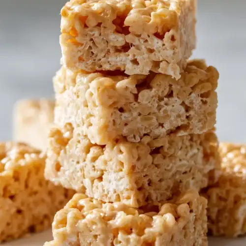 Stack of peanut butter rice krispie treat bars on white marble background